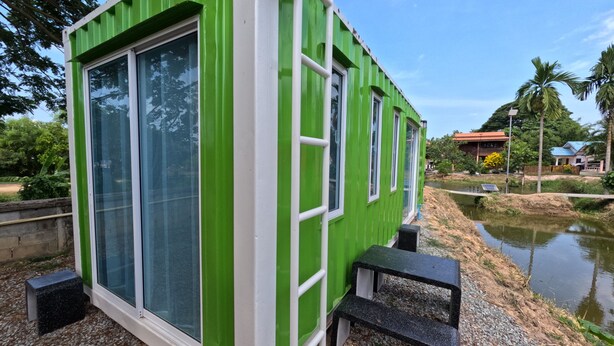 Un edificio de estilo contenedor con grandes ventanales, un escalón pequeño y un camino de grava.