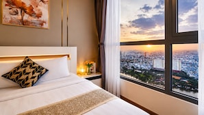 Habitación de hotel con una cama grande, vistas a la ciudad y un cuadro en la pared.