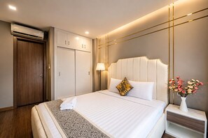 A hotel room with a bed, bedside table, lamp, and a wall-mounted air conditioner. - Bizport Serviced Apartment HousingHCMC (Ho Chi Minh City)