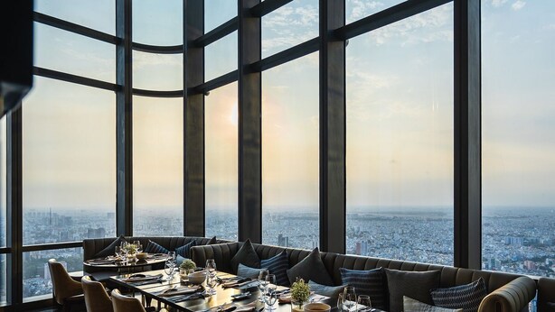 En elegant restaurang på en hög våning med en fantastisk panoramautsikt över staden, stora fönster och en modern inredning.