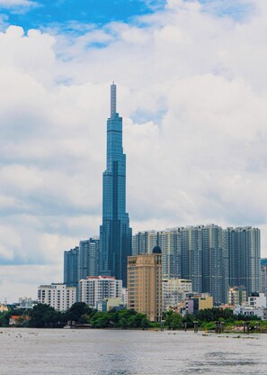 A cityscape with a prominent skyscraper, several mid-rise buildings, and a body of water in the foreground. - Bizport Serviced Apartment HousingHCMC (Ho Chi Minh City)