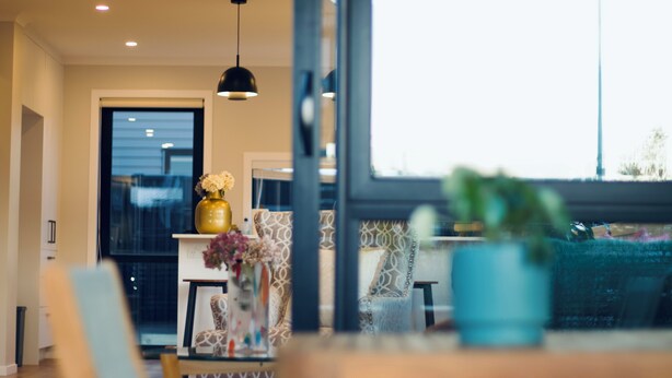 A modern interior with a dining area, a large window, and a hanging pendant light. - Modern 3-Bedroom Family Home Near Racecourse & Brewtown (Upper Hutt)
