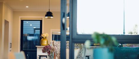 A modern interior with a dining area, a large window, and a hanging pendant light.