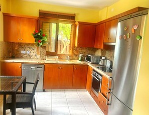 Eine Küche mit Holzschränken, einem Edelstahlkühlschrank, einer Mikrowelle und einem Geschirrspüler.