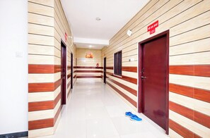 A hallway with wooden paneling, a sign indicating room number 101, and a blue object on the floor. - Hotel Ramesht Home Stay Near Kashi Ghat  (Varanasi)