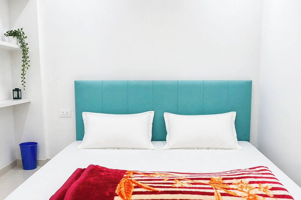A bed with a teal headboard, white pillows, and a striped blanket.