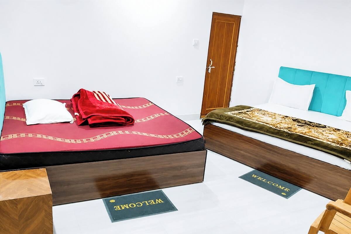 A hotel room with a bed, a wooden headboard, a door, and a welcome mat.