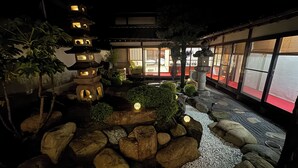 Un jardín japonés tradicional con faroles de piedra, una pagoda y una casa de té.