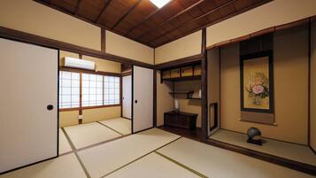 Una habitación japonesa tradicional con suelo de tatami, puertas correderas, techo de madera y aire acondicionado de pared.