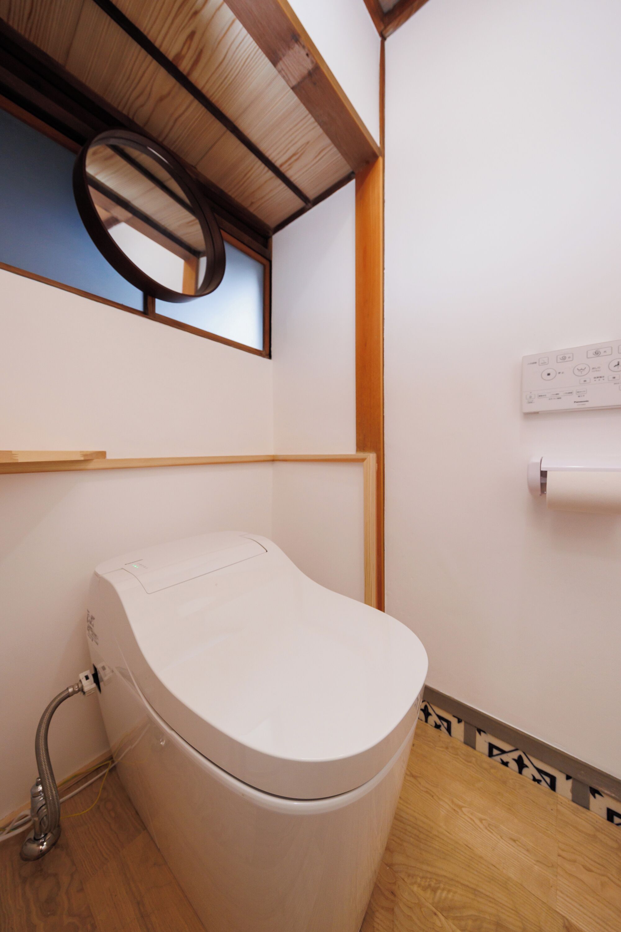 A small, compact bathroom with a toilet, a mirror, and a window.