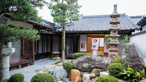 Un edificio japonés tradicional con tejado de tejas, linternas de piedra y un jardín de rocas.