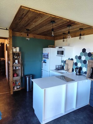 Una cucina con isola centrale, soffitto in legno e un forno a microonde sopra.