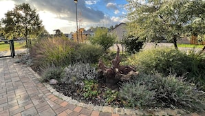 A paved walkway with a garden area featuring various plants and a lamp post. - Vacation apartment on the Arendsee with balcony (near the lake, very quiet location (Arendsee (Altmark))