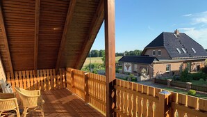 A wooden deck with chairs, a railing, and a view of a house with a tiled roof. - Vacation apartment on the Arendsee with balcony (near the lake, very quiet location (Arendsee (Altmark))