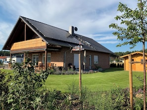 A two-story wooden house with a sloped roof, a covered porch, and a well-maintained lawn.
