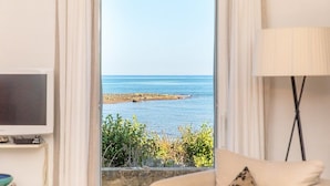 A room with a TV, a lamp, and a view of the sea through a doorway. - Villa Numia A: A bright and sunny two-story independent house located right on the beach, with Free WI-FI. (Ostuni)