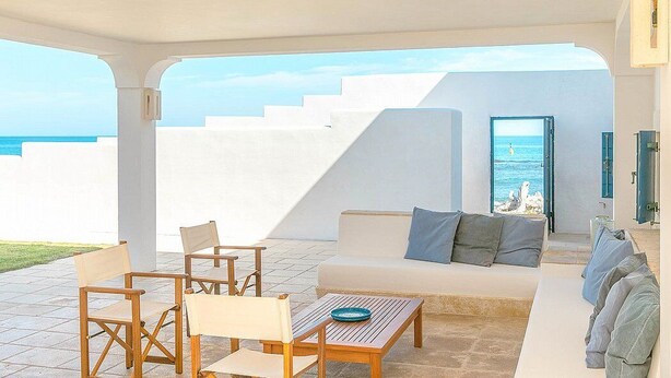Ein moderner Außenbereich mit einer weißen Couch, Holzstühlen und einem Tisch.
