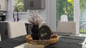 A modern kitchen with grey cabinets, a black faucet, and a window with blinds. - South KC upscale Corporate Rental (Grandview)