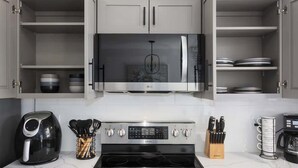 A kitchen with a microwave, stove, and various utensils. - South KC upscale Corporate Rental (Grandview)