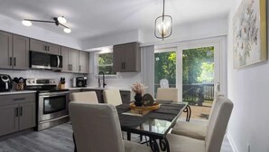 A modern kitchen with a dining area, stainless steel appliances, and a view of the outdoors. - South KC upscale Corporate Rental (Grandview)