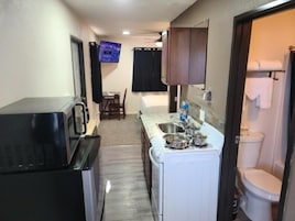 Cocina compacta con microondas, lavamanos y un pequeño comedor.