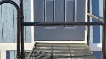Uma escada de metal posicionada diante de uma porta azul com a letra 'B'.