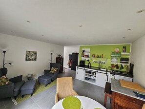 En moderne stue med sofa, skammel og spisebord med grønne detaljer.