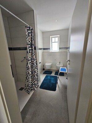 Et badeværelse med bruser, toilet, bidet og håndvask.