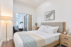A modern bedroom with a bed, bedside tables, a lamp, and a framed map of Toronto on the wall. - CN Tower View -Central DT (Toronto)