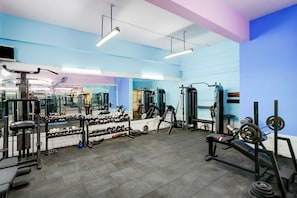 Een sportschool met diverse fitnessapparaten, spiegels en een blauw-wit kleurenschema.