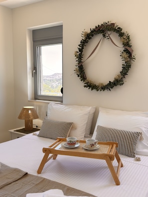 A bedroom with a bed, bedside table, lamp, and a decorative wreath on the wall. - Home22 | Sea, Pool & Serenity, Rhodes (Rhodes)