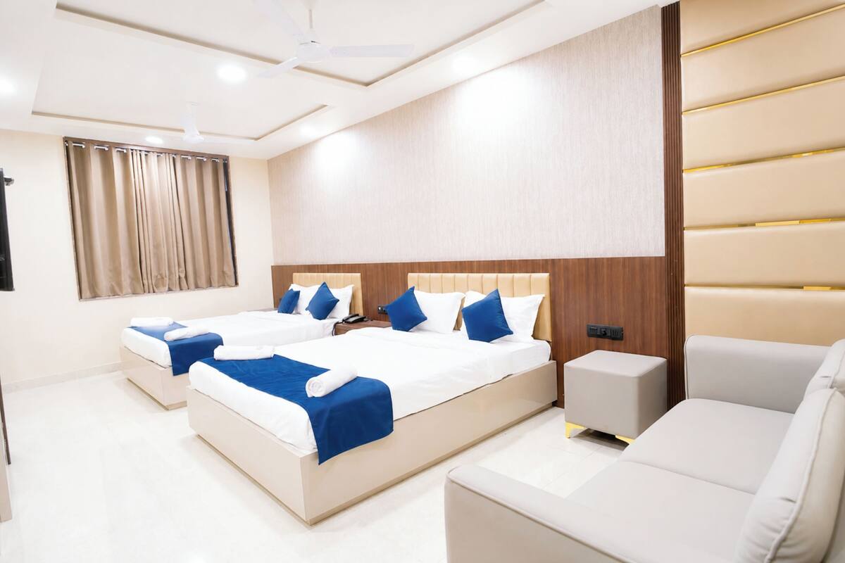 Una habitación de hotel moderna con dos camas, un sofá, una mesita y un ventilador de techo.