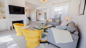 Una sala de estar moderna con un sofá, sillones amarillos, una chimenea y un televisor.