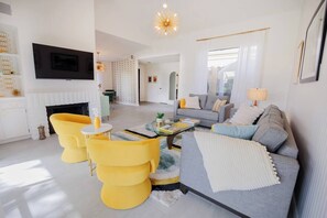 A modern living room with a sofa, yellow chairs, a fireplace, and a TV. - 2 Pools, Golf View, 2 Kings, 1 Full, 1 Twin, Luxury Home (Palm Desert)