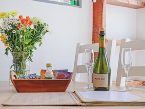 Ein Tisch mit einer Weinflasche, zwei Gläsern, einer Blumenvase und einer Holzkiste mit Snacks.