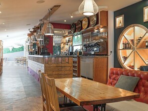 Un restaurant doté d’un bar en bois, d’un espace salon et d’un présentoir à vins.