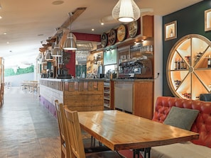 A restaurant with a wooden bar, seating area, and a wine display. - Truffle House - UKC9375 (Westward Ho!)