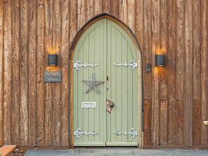 Una puerta de madera con una decoración de estrella, un letrero que dice 'The Truffle House' y dos luces fijadas a la pared.