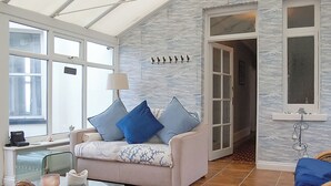 A room with a sofa, a glass coffee table, and a stone centerpiece. - Bryn Eglwys - UKC9411 (Barmouth)