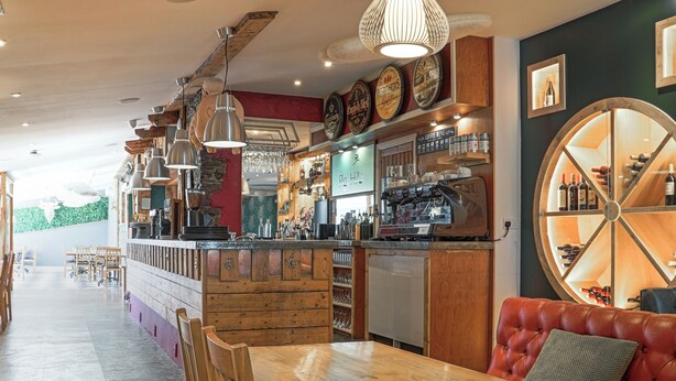 Un restaurant doté d’un bar en bois, d’un espace salon et d’un présentoir à vins.