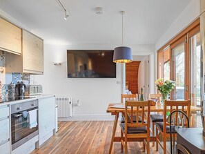 Eine moderne Küche mit Backofen, ein Essbereich mit Holzmöbeln und ein großes Fenster mit Blick.