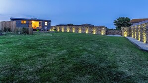 Et moderne hus med velplejet græsplæne, stenvægge og et træhegn.