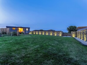 A modern house with a well-maintained lawn, stone walls, and a wooden fence. - Looking for a romantic getaway. (St Buryan)
