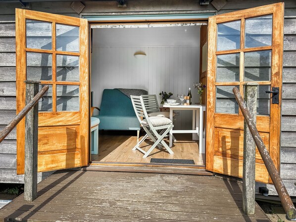 A wooden door with glass panels, a small table with a chair, a bed, and a wall-mounted light fixture. - Looking for a romantic getaway. (St Buryan)