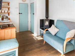 A cozy living room with a blue sofa, wooden floor, and a wood-burning stove. - Looking for a romantic getaway. (St Buryan)