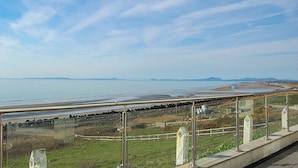 Une vue sur la côte, avec un ciel dégagé, une plage et une route qui s’étend au loin.
