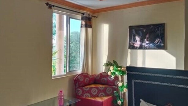 Une pièce comprenant un lit, une fenêtre avec des rideaux, une petite table et un tableau accroché au mur.