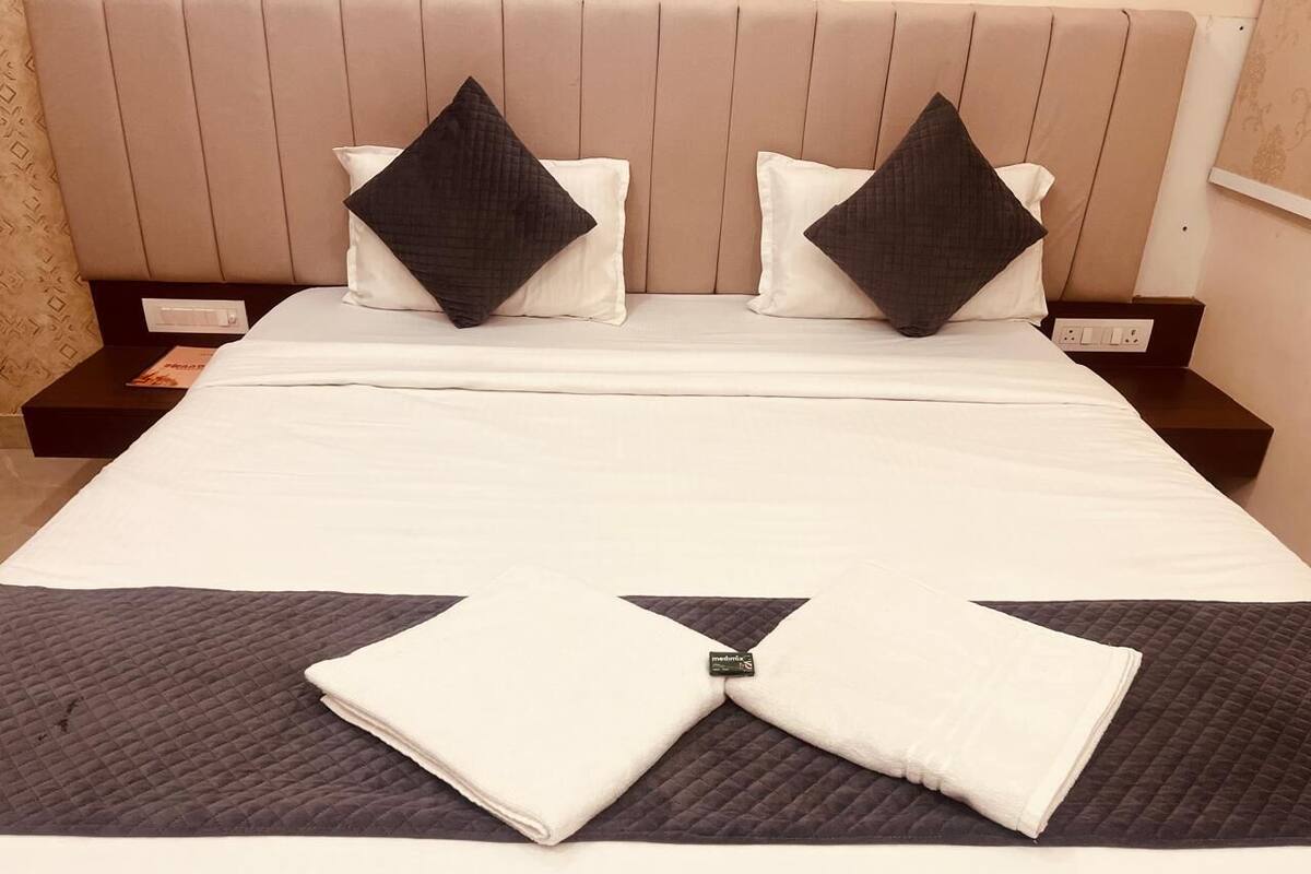 A neatly made bed with a folded white towel in the center, two pillows, and a headboard.