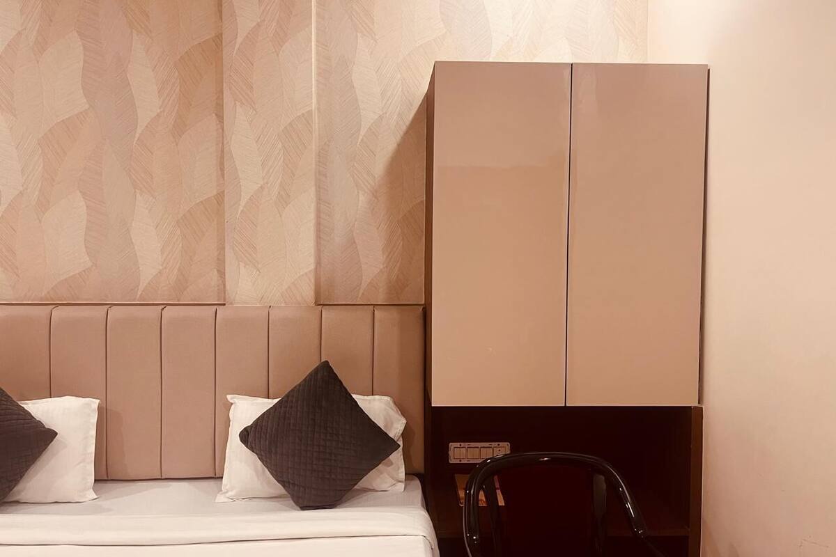 A hotel room with a bed, pillows, a wardrobe, and a nightstand.