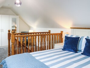 A bedroom with a wooden staircase, a bed with striped bedding, and a nightstand with a lamp. - 1 bedroom accommodation in Narberth (Narberth)